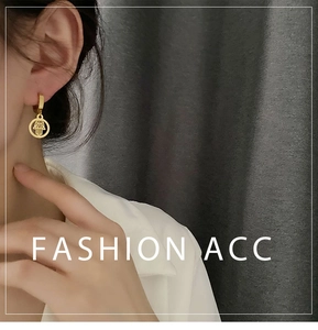 Detail of gold Hamsa Hand charm hanging on geometric titanium steel hoop earrings