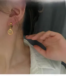 Close-up of gold Hamsa Hand earrings on a model showing the hollow geometric design