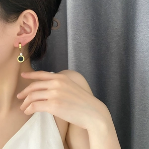 Boucles d'oreilles dorées à chiffres romains avec pendentif zircon noir sur un mannequin