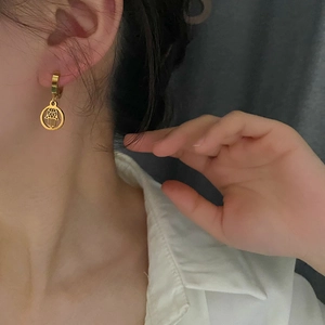 Golden titanium steel hoop earrings with Hamsa hand charm shown on a female model
