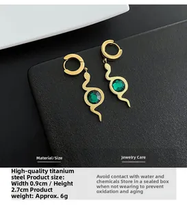 Detail view of gold titanium snake earrings with green zircon and hammered texture