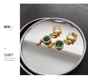 Detail of snake drop earrings in gold finish with a sparkling green zircon stone