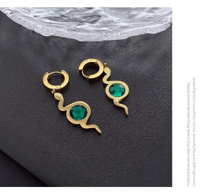 Detail view of gold snake earrings featuring scale textures and green zircon stones