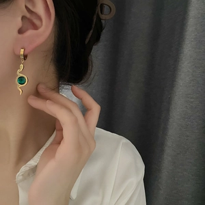 Snake drop earrings in hammered gold finish with green zircon, worn by a model