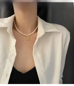 Detailopname van een parelketting met gouden beerhanger en gegraveerde letter B detail