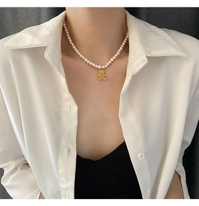 Detailopname van parelketting met gouden beertje hanger en gewatteerd patroon bij een model