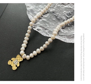 Detail van zoetwaterparelketting met gouden berenhanger met gewatteerde textuur en B-logo