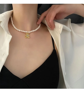 Detail van een parelketting met gouden beer hanger en letter B op een model
