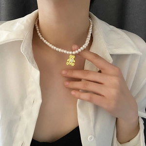 Prachtige parelketting met gouden beer hanger en letter B detail gedragen door model