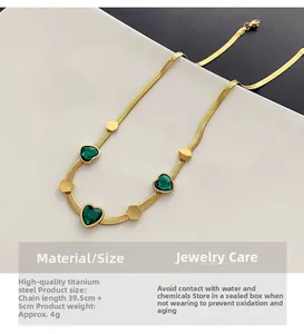 Close-up of golden snake chain with green heart gems and hexagonal charms in titanium steel