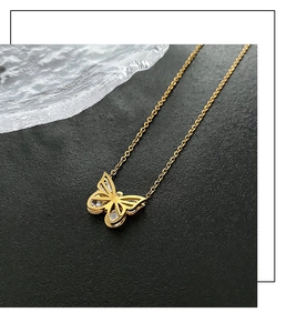 Gros plan du pendentif papillon doré orné de cristaux sur une fine chaîne maille forçat