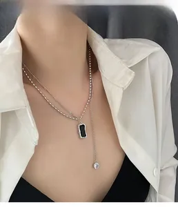 Detail of minimalist silver double layer necklace with black rectangle pendant on a model