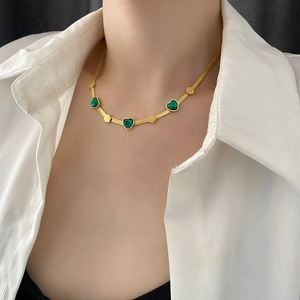 Elegant gold snake chain necklace with three emerald heart pendants on a model