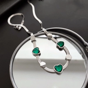Elegant silver snake chain necklace featuring three green heart gemstones and metal accents