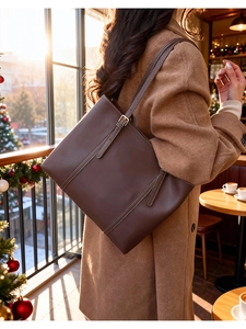Detail of deep brown leather tote bag featuring contrast stitching and adjustable metal buckle