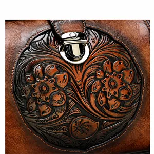 Close-up of vintage embossed floral pattern and silver metal lock on brown leather bag