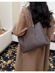Detail of dark brown leather tote bag with contrast stitching on autumn street scene