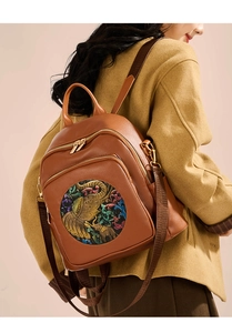 Brown leather backpack with colorful elephant embroidery shown on a model's back