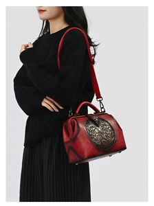 Detail of red vintage leather doctor bag featuring intricate heart floral metal embossing