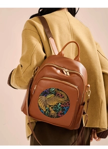 Detailed view of brown leather backpack with colorful elephant embroidery on a model