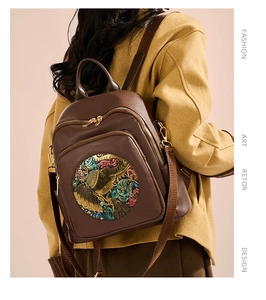 Detail of soft brown leather backpack with colorful elephant relief and artistic patterns