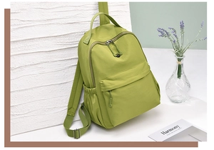 Detail of water-resistant green nylon backpack with front pocket and side drawstring pocket