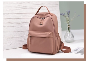 Detail of pink waterproof nylon backpack showing front zipper pocket and side pockets