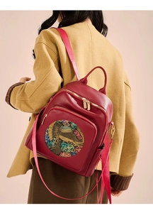 Detailed view of red pebble leather backpack with artistic elephant print and zippers