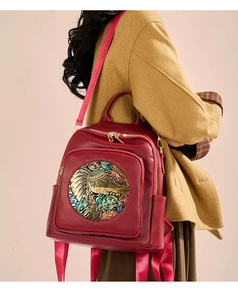 Detail of red pebbled leather backpack with golden elephant relief and ethnic motif
