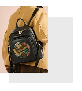 Detail of black leather backpack featuring colorful floral embossed elephant pattern