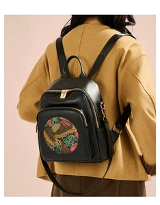 Detail of black pebbled leather backpack with colorful elephant design on camel coat