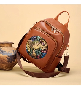 Detail of a brown leather backpack with colorful elephant and floral embossed patterns