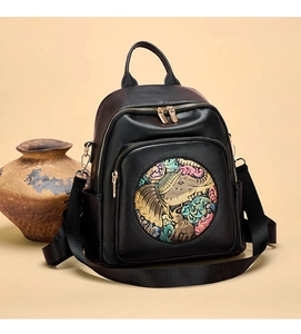 Detailed view of black leather backpack featuring colorful embossed elephant art pattern