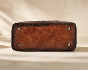 Macro view of vintage brown leather bag base featuring four bronze protective metal studs
