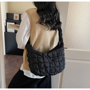 Détail du sac nuage noir matelassé montrant la texture bouffante sur l'épaule d'une femme
