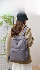 Rear view of a model wearing a grey-purple waterproof nylon backpack with large capacity