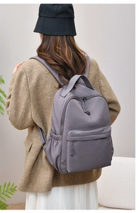 Rear view of a model wearing a grey nylon backpack with a minimalist casual design