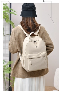 Cream nylon backpack with large capacity worn by model in a minimalist setting