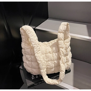 Détail du sac matelassé crème montrant la texture des coutures carrées et le tissu en nylon