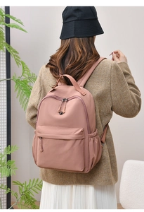 Rear view of a model wearing the pink water-resistant nylon backpack for travel and school