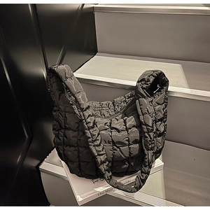 Gros plan du sac nuage noir matelassé avec texture bouffante en nylon et bandoulière souple