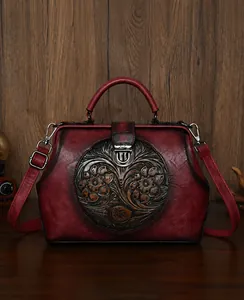 Close-up of vintage embossed floral pattern and retro metal clasp on dark red leather bag