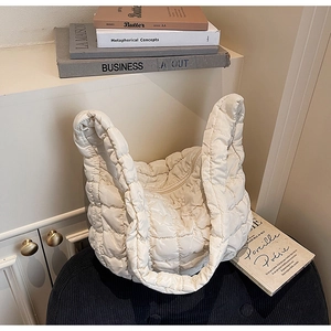 Sac bouffant matelassé beige sur un siège avec fond de magazines élégants