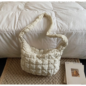 Gros plan sur la texture du sac nuage matelassé beige et sa bandoulière intégrée