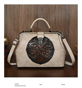Detail of vintage beige doctor bag with embossed floral ornament and bronze hardware