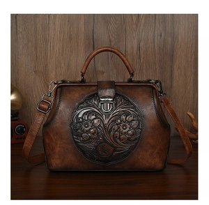 Close-up of vintage brown leather handbag featuring intricate floral embossed details