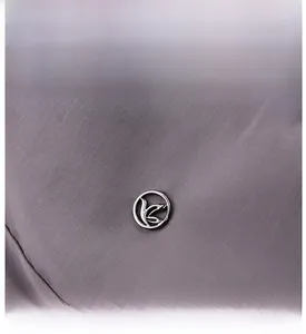 Close-up of waterproof plaid nylon fabric and round metal logo on a backpack