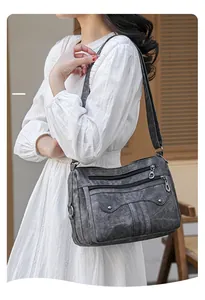 Detail view of dark grey retro crossbody bag with dual zippers and textured finish
