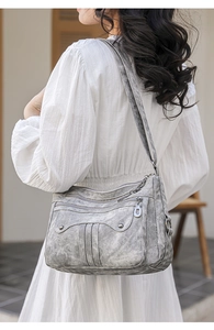 Detail of grey multi-pocket shoulder bag with metal rivets and washed texture design