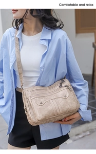 Detail of khaki multi-pocket crossbody bag showing zippers and soft washed texture
